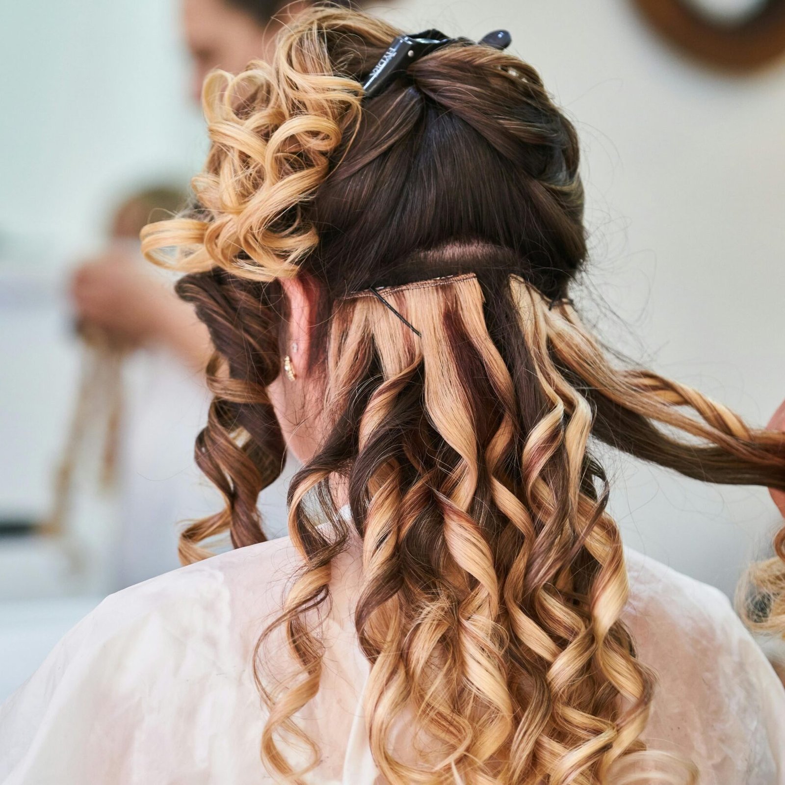 Close-up of hairstylist perfecting curls on a woman's hair in a salon setting.
